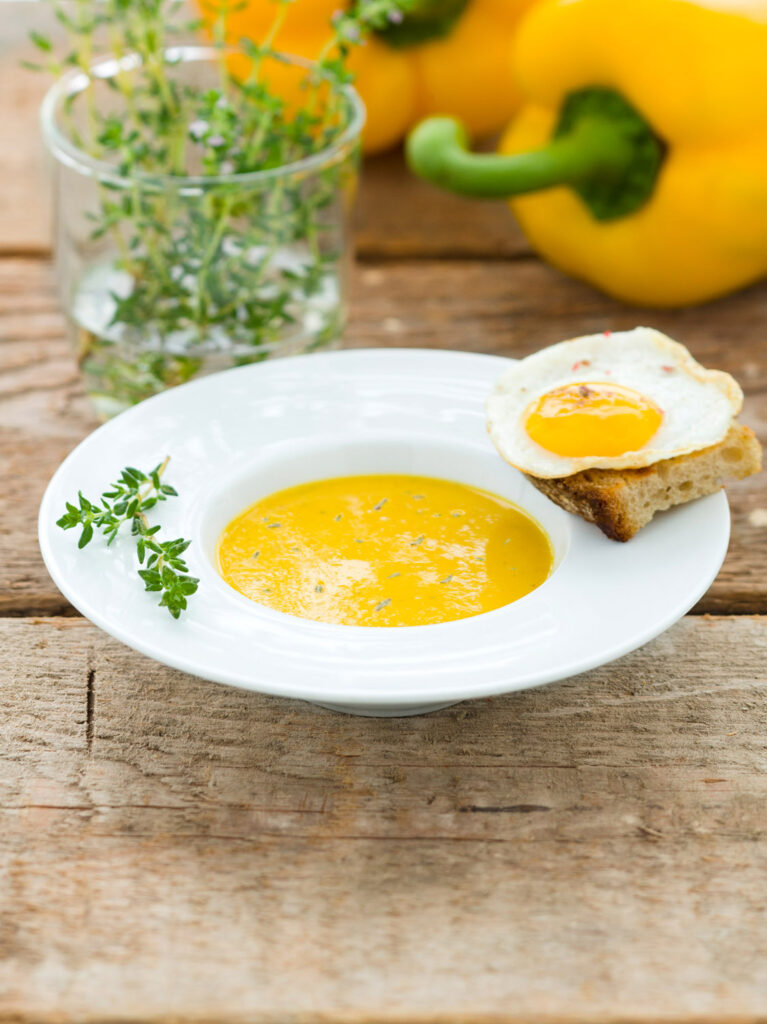 photo culinaire d'aperitif, avec une soupe froide Alvalle dans une assiette blanche et une tartine avec un oeuf dessus.
