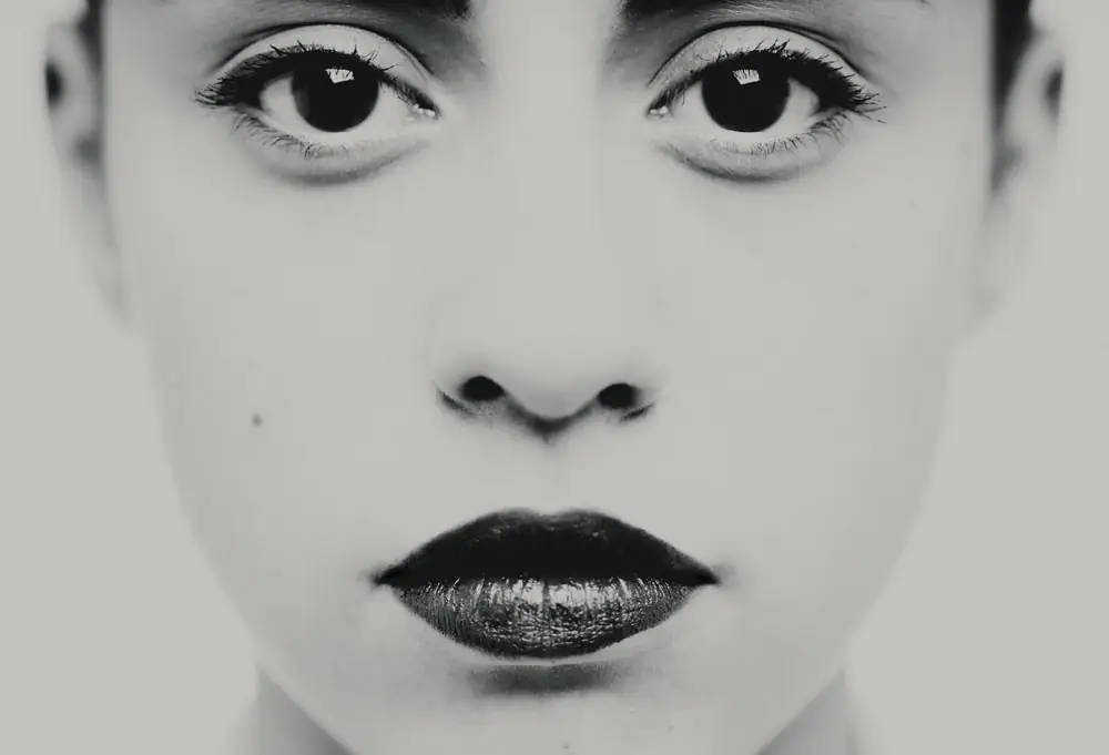 Portrait artistique noir et blanc en studio à Bordeaux : gros plan visage, levres maquillees, regard accentue, rendu high key. Photographe portrait beaute.