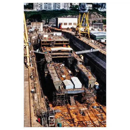 Vue aérienne d'un chantier naval avec grues jaunes, navires en cale sèche et échafaudages