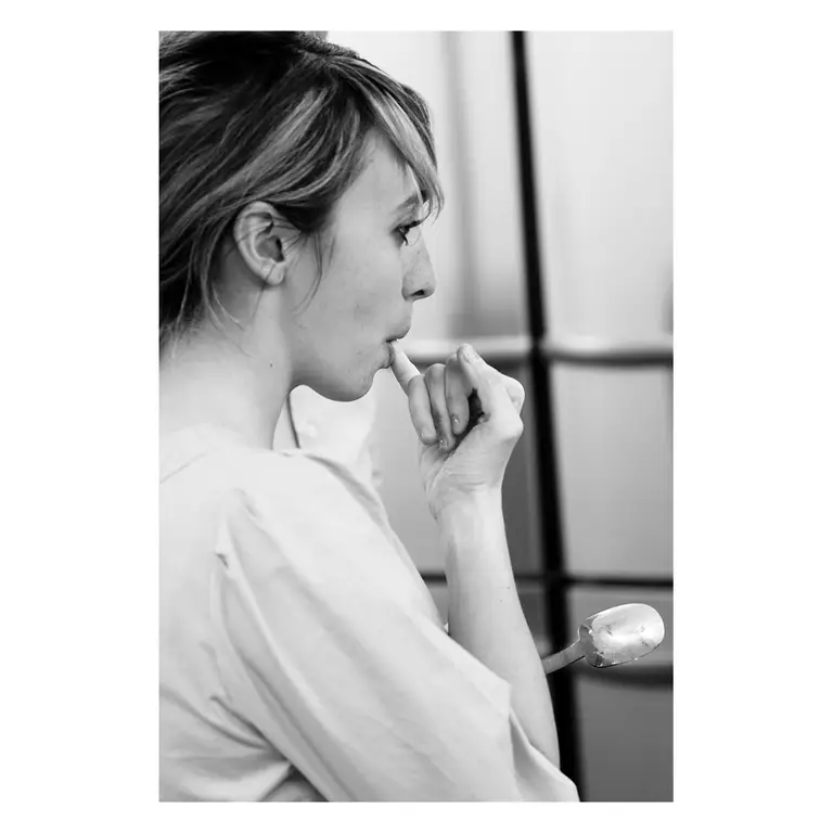 Dégustation d’une élève en cuisine goutant une recette, instant gourmand en noir et blanc lors d’un reportage photo culinaire.