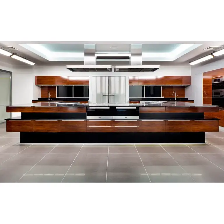 Cuisine moderne de showroom, grand îlot central, façades bois et noir, plans en inox, double réfrigérateur portes françaises, fours encastrés, éclairage plafond, sol carrelage gris, vue frontale symétrique, dans un style d’architecture design.