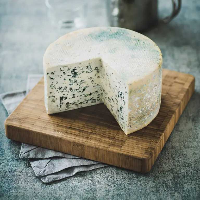 Fromage bleu artisanal, d’une meule entamée sur planche  en bois avec une lumière naturel, fait par un photographe professionnel.