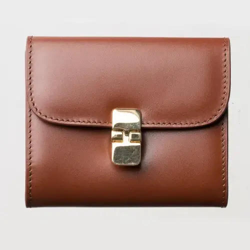 Portefeuille compact en cuir lisse marron, vue face, fermoir métal doré détouré sur fond blanc — packshot e-commerce avant retouche.