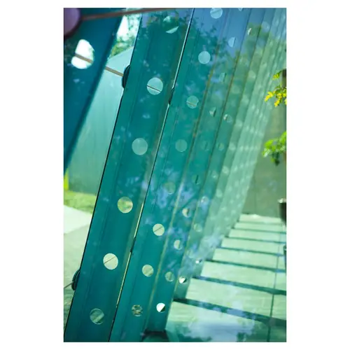 photographie d’architecture,, avec un gros plan sur des lames de verre teinté vert, ponctuées de pastilles sérigraphiées, révélant la trame et la transparence de la façade.