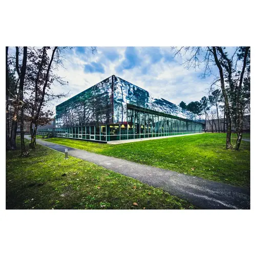 photographie d’architecture, d’ un angle d’un volume à effet miroir sous ciel chargé, parc dégagé et cheminement piéton.