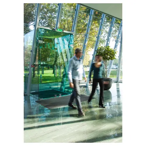 photographie corporate, d’un intérieur avec sas et porte en verre, sol brillant, silhouettes floues de collaborateurs, ambiance de transparence.