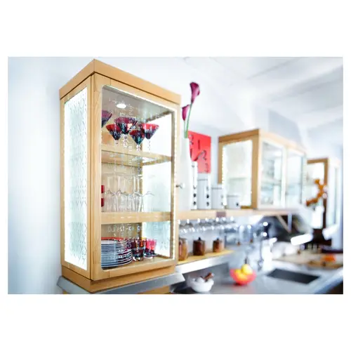 Vitrine en verre éclairée avec verres et vaisselle dans une cuisine moderne.