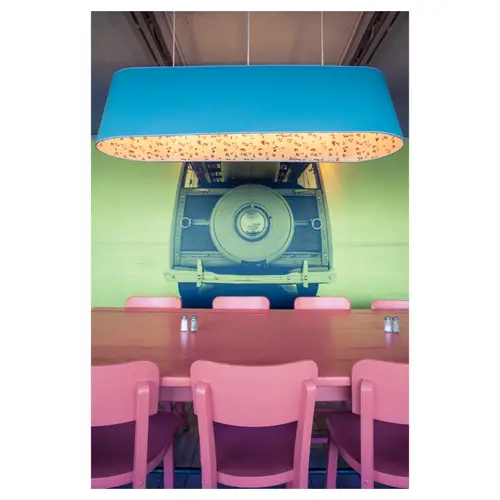 reportage décoration intérieur d'un restaurant design chaises roses lampe bleue avec déco murale d'une voiture