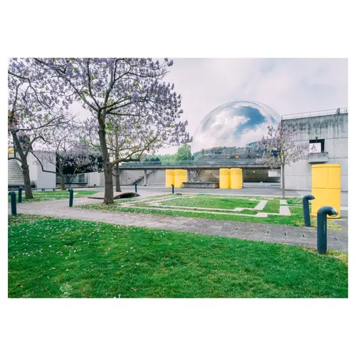 parc urbain béton avec des arbres en fleurs au printemps, très graphique, avec sphere miroir de la villette