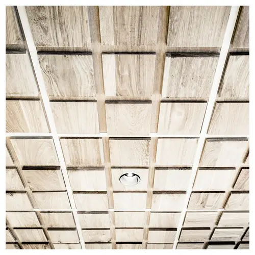 Détail de plafond modulaire en bois avec spot encastré — aménagement intérieur de librairie à Paris, photographie d’architecture.
