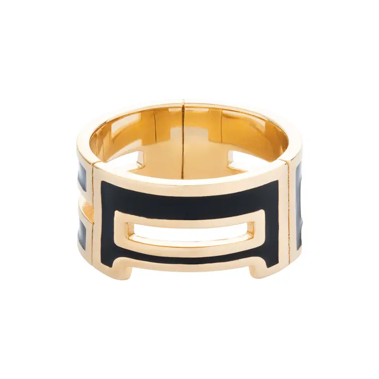 Photo packshot d’une bague large dorée avec détails en émail noir, fond blanc