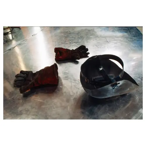 Gants de soudeur uses et masque de protection sur sol métallique de chantier naval