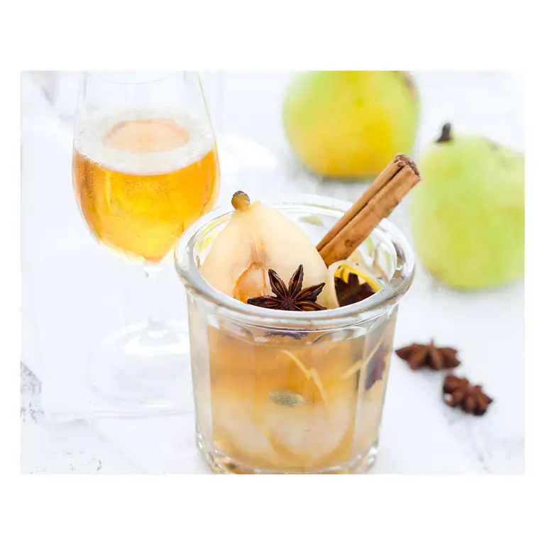 Poire pochée aux épices (cannelle, badiane, cardamome) dans bocal, flûte de cidre en arrière-plan dans des tonalités claires, photographié par un photographe culinaire.