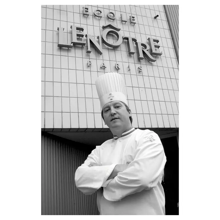 Portrait d’un chef devant une façade d’école culinaire en noir et blanc, présentation corporate.