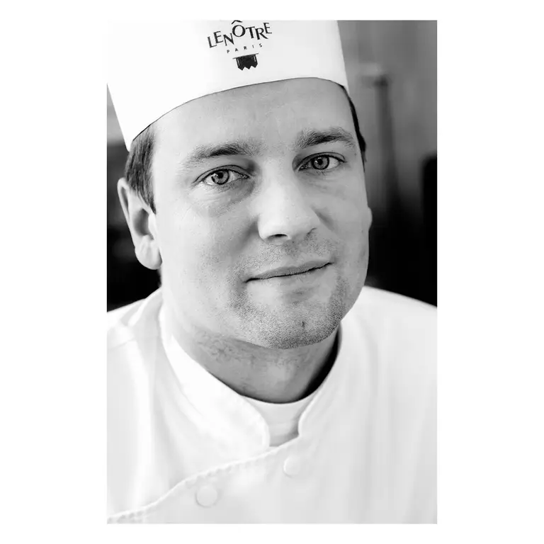 Portrait d’un chef pâtissier en veste blanche, reportage en noir et blanc dans un école de cuisine.