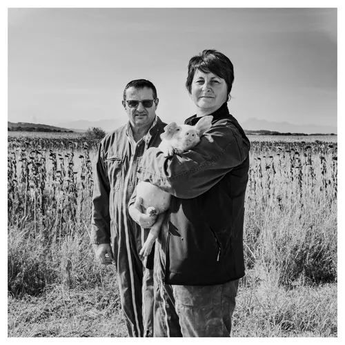 portraits corporate d'éleveurs, tenant un porcelet dans un champ, photo noir et blanc
