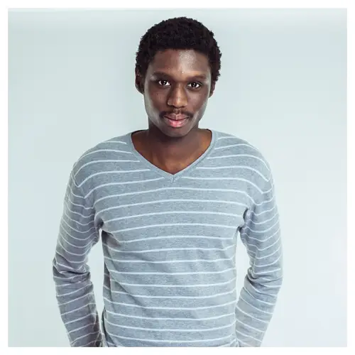 Portrait CV en studio à Bordeaux d'un homme en pull à rayures grises, regard caméra par un photographe professionnel.