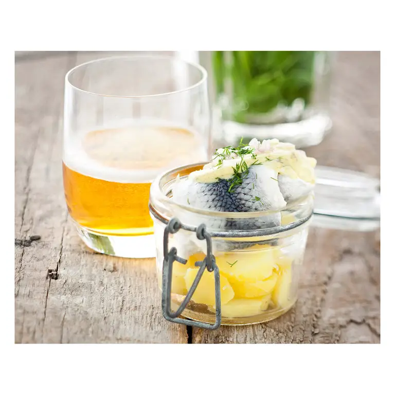 Verrine fermée remplie de pommes en dés et poisson mariné à l’aneth, servie avec verre de cidre doré sur une table en bois rustique.