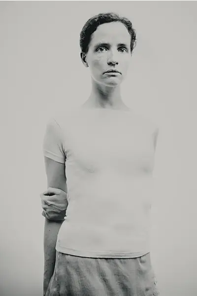 Portrait studio noir et blanc en pied d’une femme au t-shirt blanc, pose minimaliste sur fond clair, regard caméra — photographe portrait à Bordeaux.