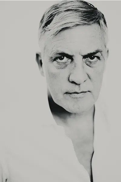 Portrait en gros plan noir et blanc d'un homme mûr regardant l'objectif, avec un col de chemise blanc.
