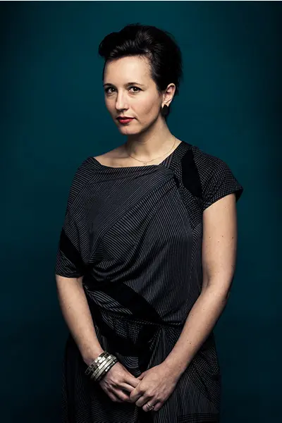 Portrait éditorial en studio d'une femme en robe à motifs graphiques sur fond bleu.