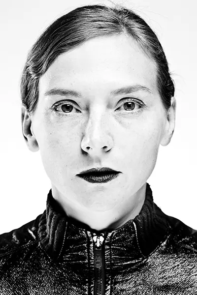 Gros plan studio en noir et blanc high key d'une femme en veste texturée au col zippé sur fond blanc.