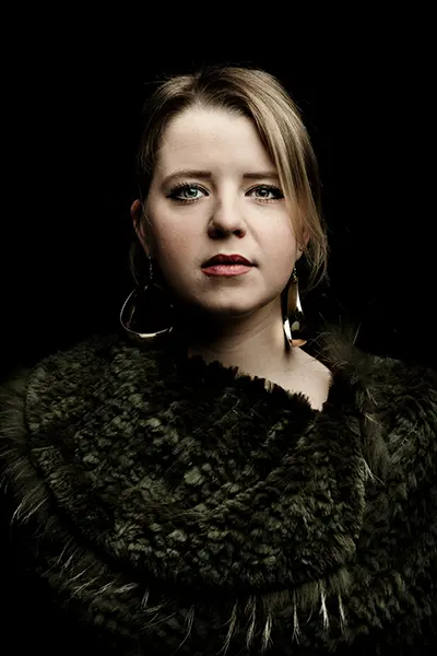 Portrait studio low key d'une femme sur fond noir, arborant de grandes boucles d'oreilles.