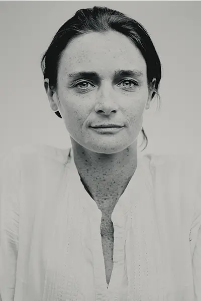 Portrait rapproché en noir et blanc d'une femme au regard direct, vêtue d'une chemise claire.