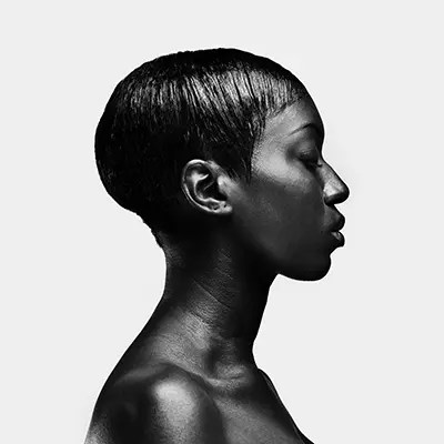 Portrait studio en profil strict noir et blanc d'une femme à la coupe courte sur fond blanc.