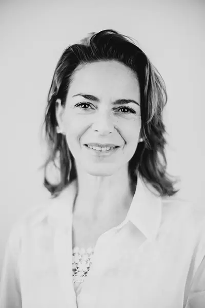 Portrait professionnel en noir et blanc d'une femme souriante en chemise blanche.