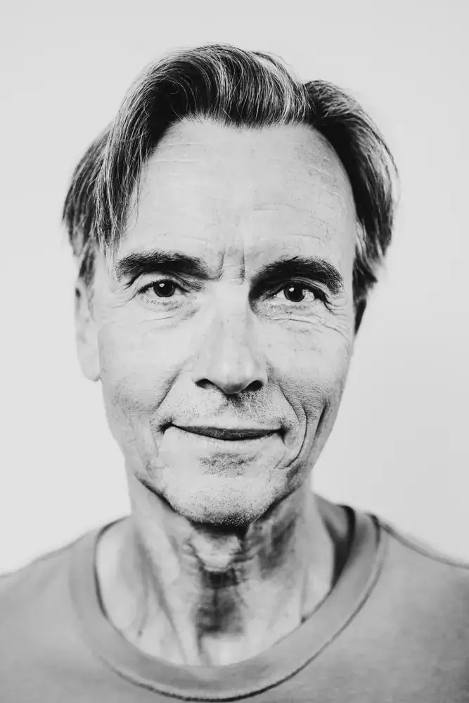 Portrait d’un homme mature en studio, rendu noir et blanc, regard direct.