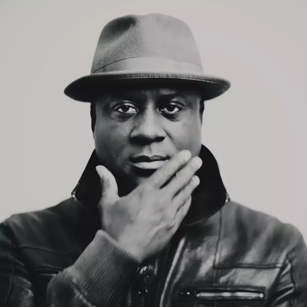 Portrait en studio d’un homme portant un chapeau et un blouson en cuir, main sur le menton, noir et blanc, réalisé à Bordeaux.